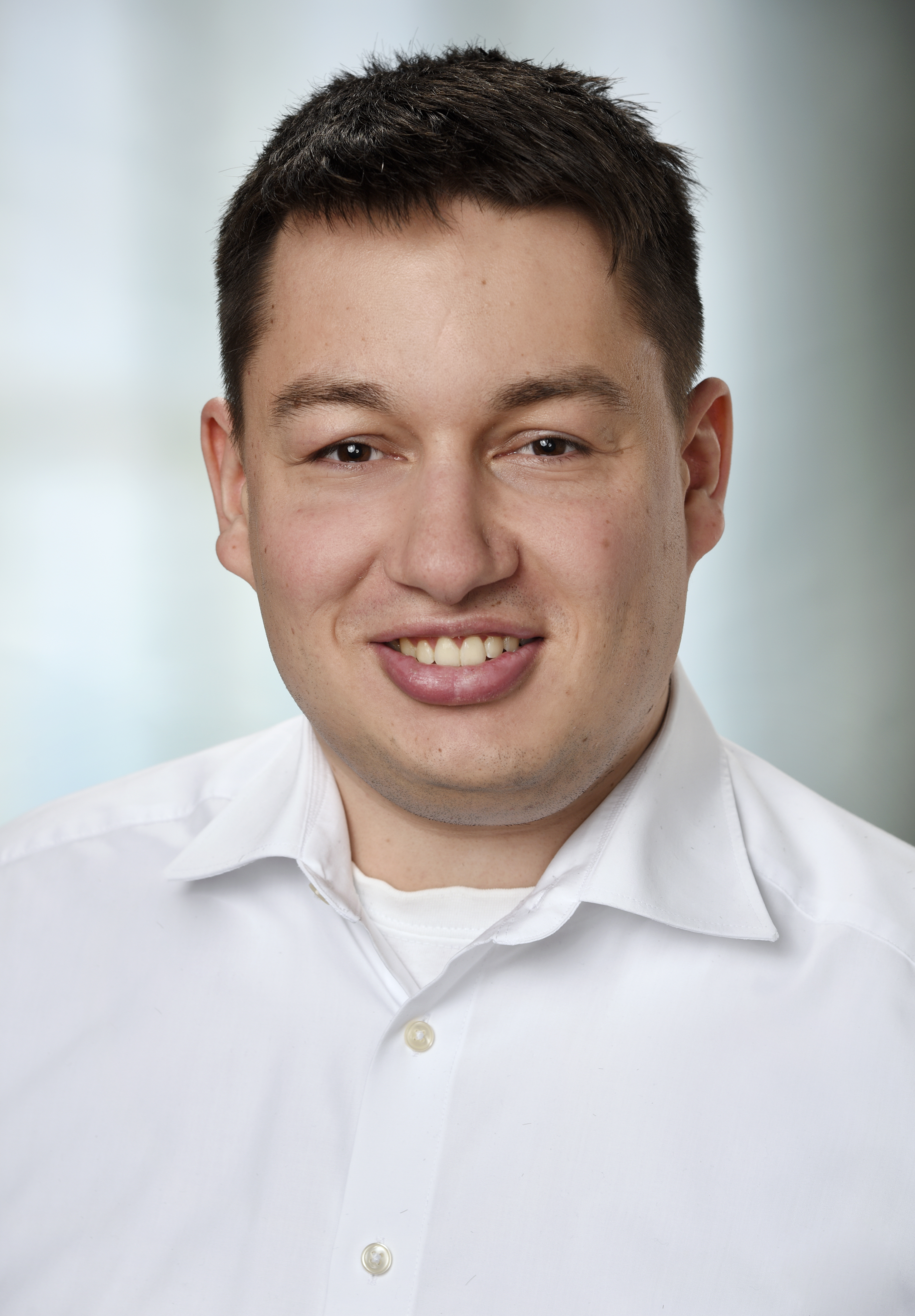 Jeanine White smiling in a red plaid shirt and tortoise shell glasses